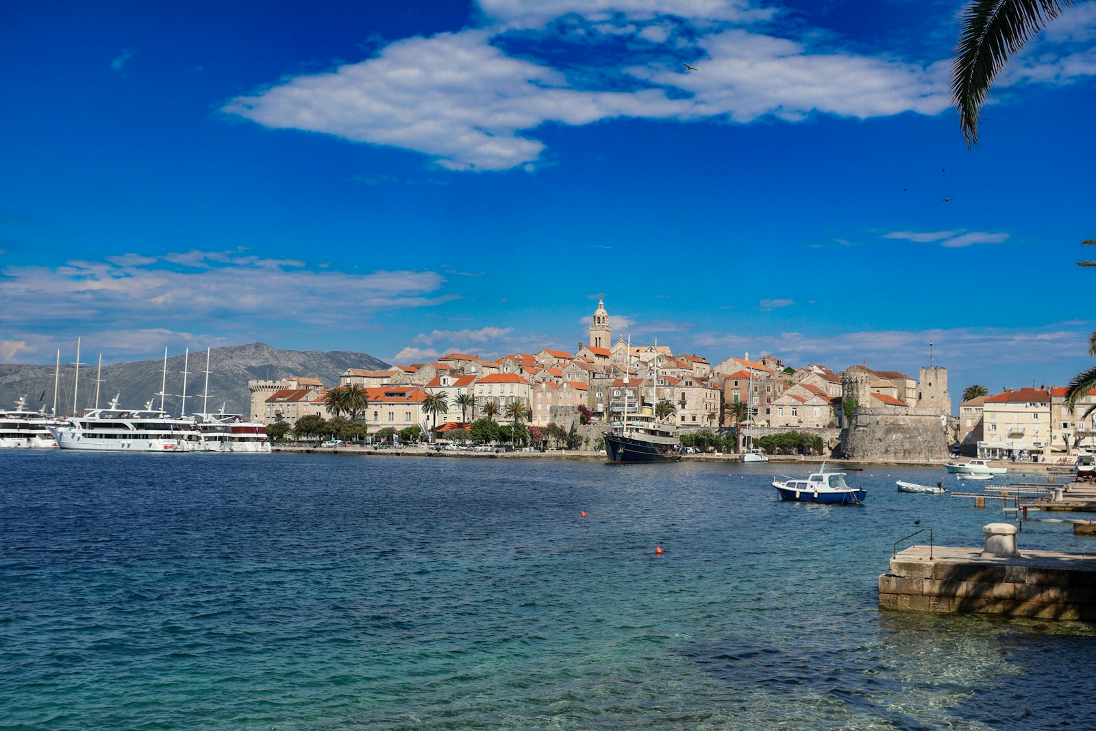 Dubrovnik to Hvar yacht route — motor yacht moored near Korčula old town at dusk with warm stone walls and harbour lights reflected in calm water